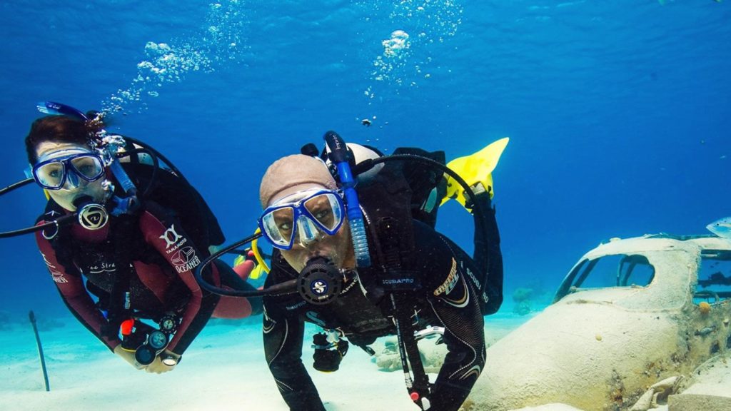 man and woman SCUBA diving looking at the camera